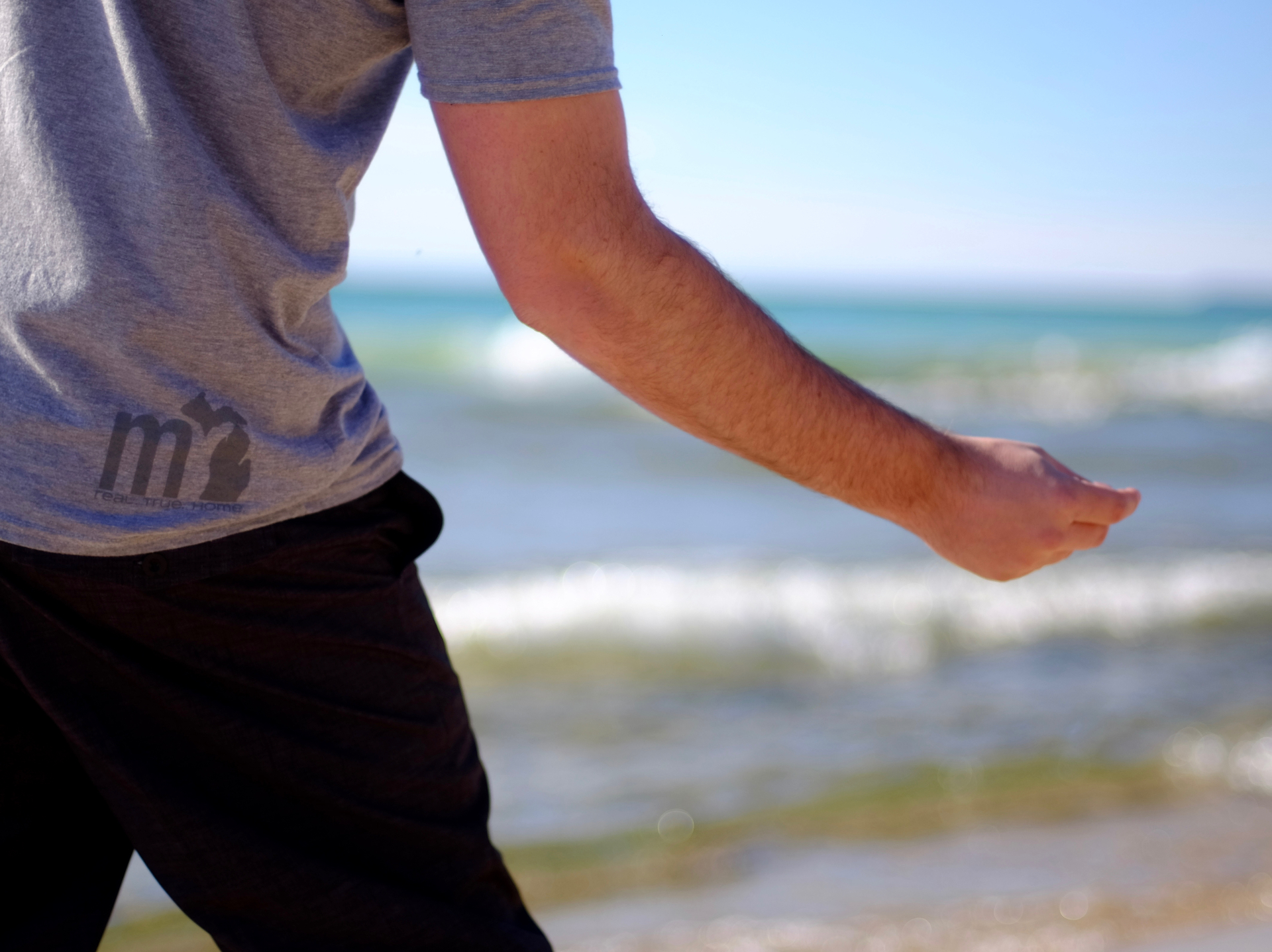 A figure in a hoodie walking the dune ridge above Lake Michigan at dawn